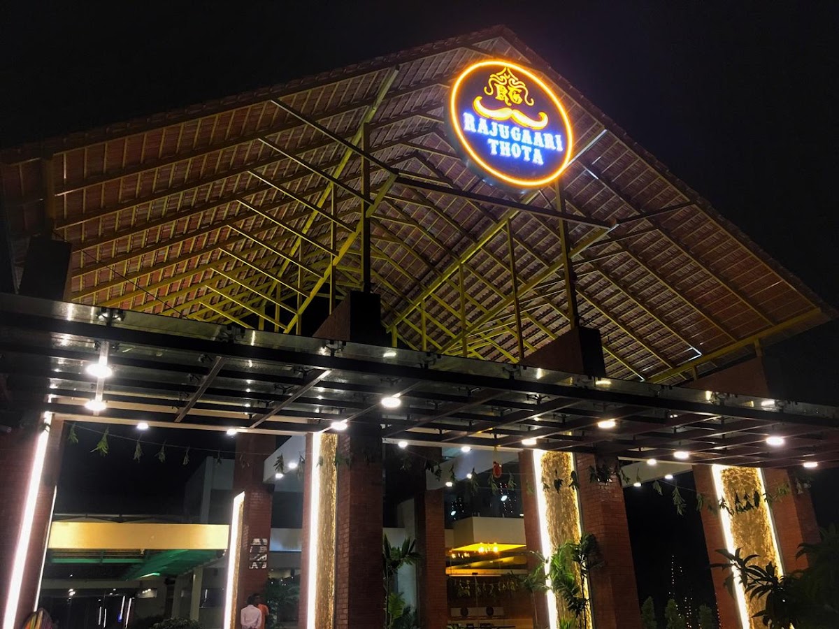 Rajugaari Thota at night — the Manduva roof and glowing moustache sign on NH-65
